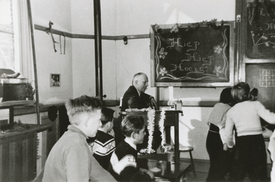 876411 Portret van bovenmeester Borra, die lachend toekijkt bij een toneelstukje opgevoerd door enkele van zijn ...